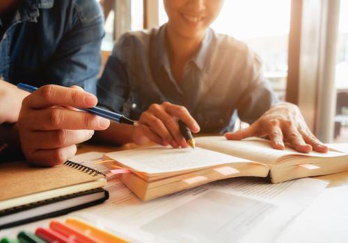 Dos personas escribiendo sobre un papel