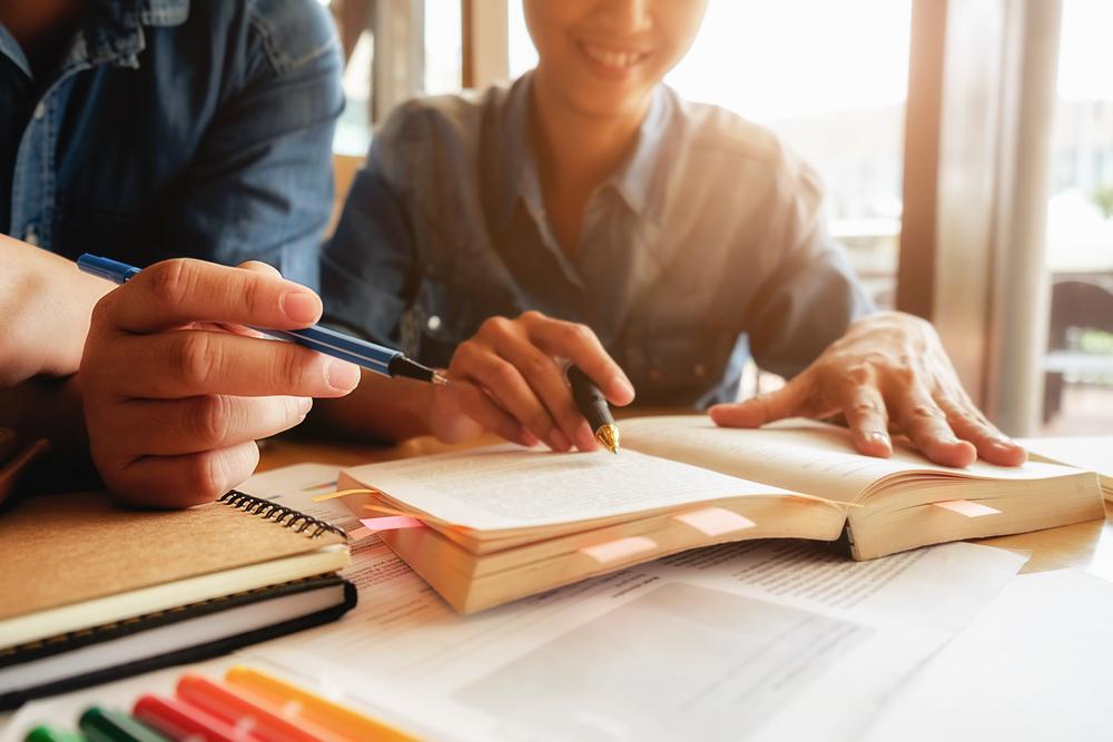 Dos personas escribiendo sobre un papel