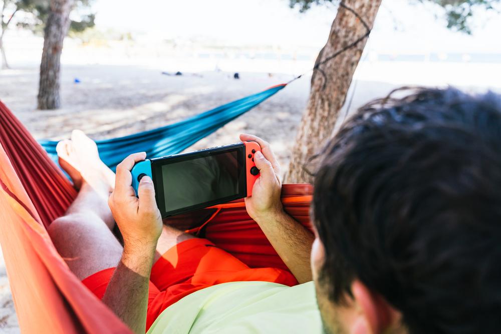 Persona jugando en la consola de Nintendo Switch sobre una hamaca