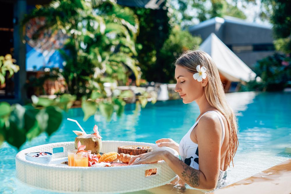 Mujer comiendo frutas en una mesa blanca redonda con un fondo verde